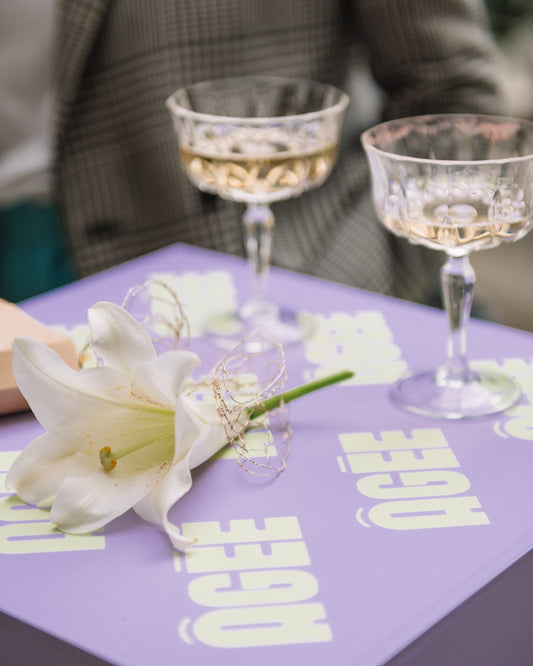 Champagne coupes and white lily on ÂGÉE printed table, launch event