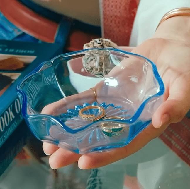 Gold rings in a blue glass bowl held in a hand, stone cleansing ritual